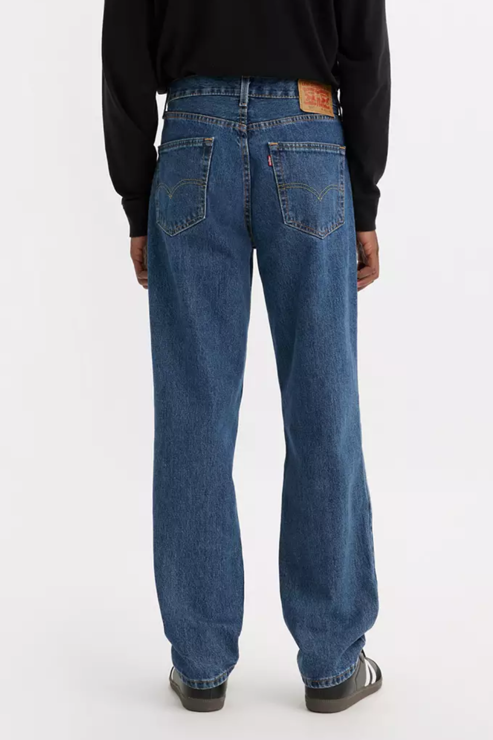 A man wearing Levi’s 550 Relaxed Fit Jeans in blue, shown from the back.