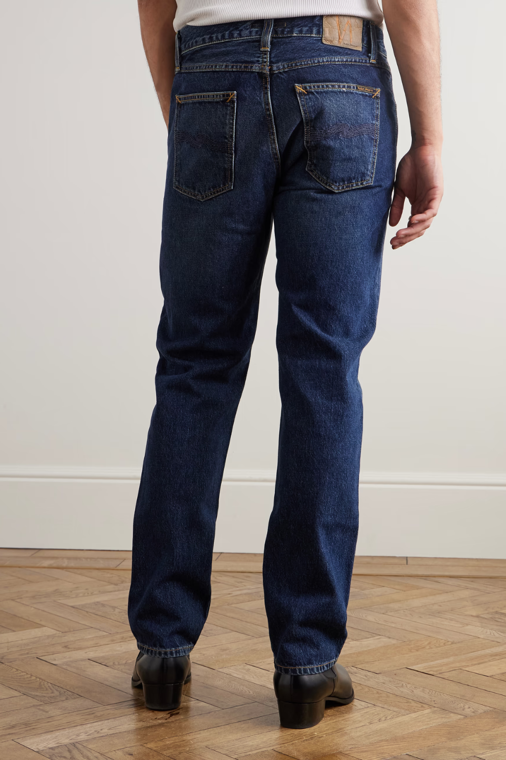 A man wearing Nudie Gritty Jackson Slim-Fit Organic Jeans in blue, shown from the back.