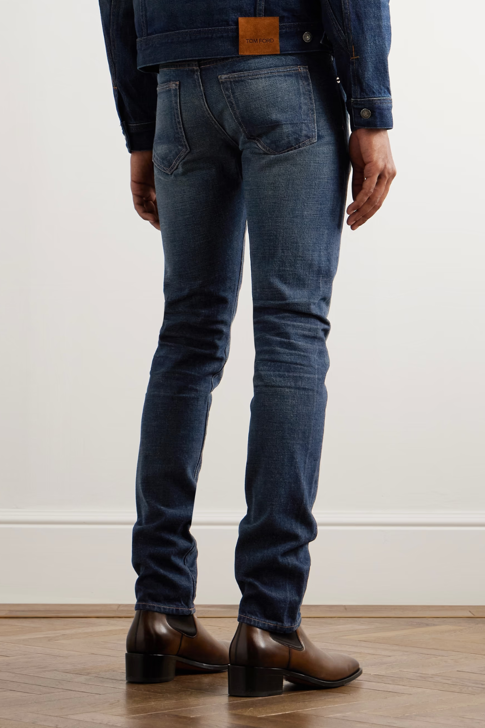 A man wearing Tom Ford Slim-Fit Selvedge Jeans in deep indigo, shown from the back.