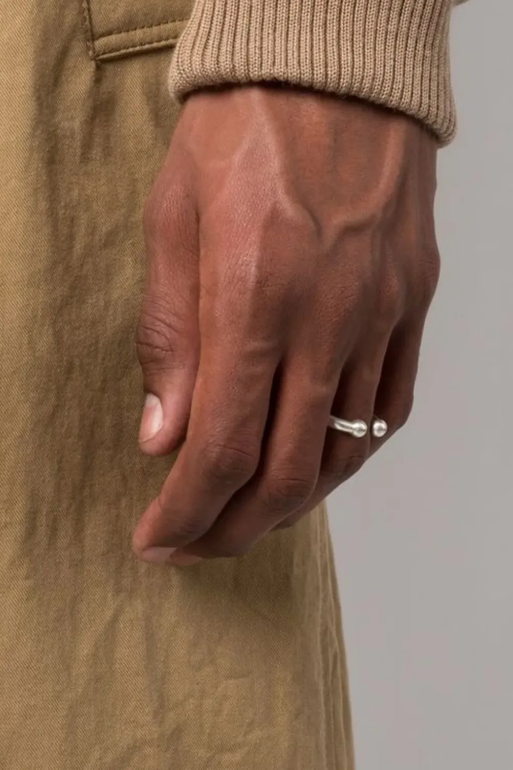Close-up shot of a man’s hand wearing the Jil Sander sterling silver open-top ring, showcasing its sculptural gap design and polished finish under natural light.