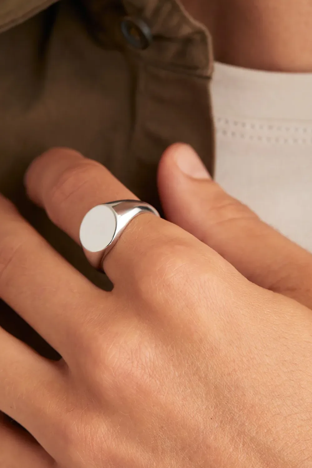 Man’s hand wearing the Mejuri Bold Round Signet Ring, a polished silver signet with a bold, rounded shape.