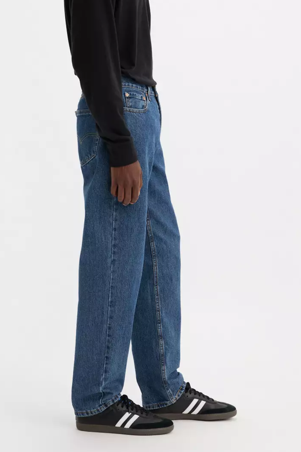 A man wearing Levi’s 550 Relaxed Fit Jeans in blue, side view.