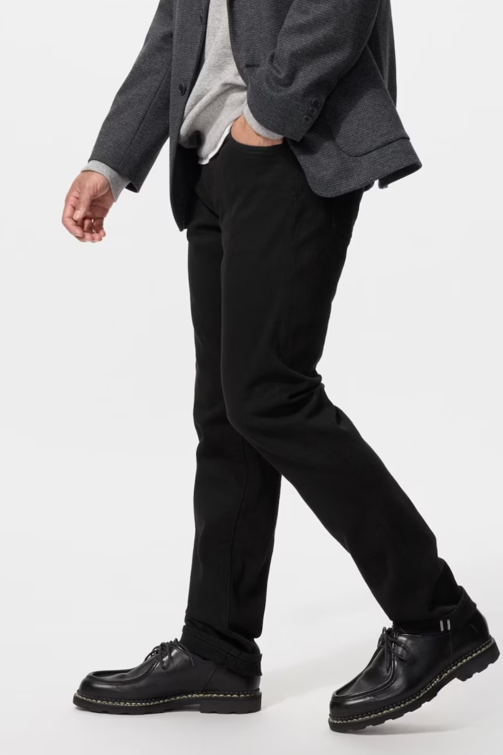 A man wearing Uniqlo Stretch Selvedge Slim Jeans in black, shown side view.