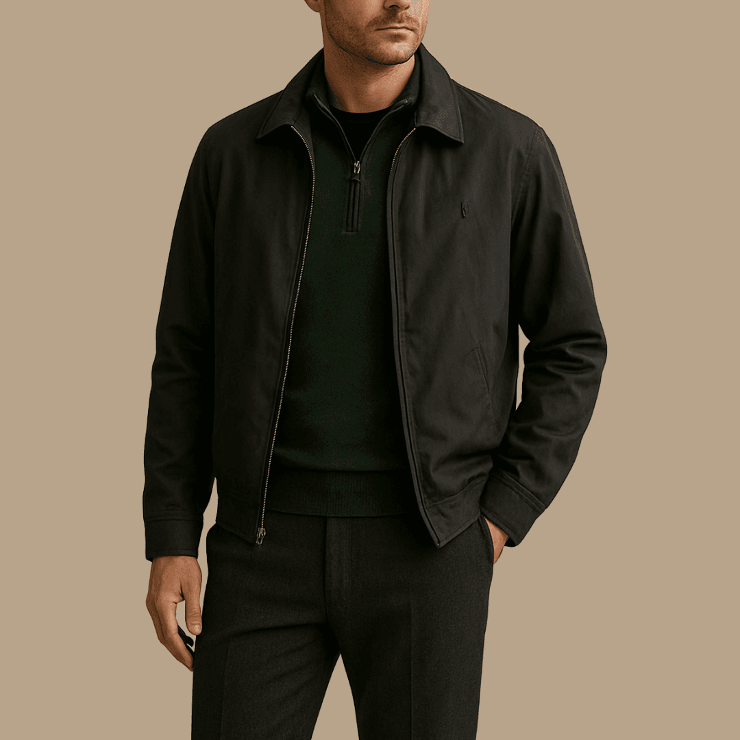 A stylish man wearing a charcoal windbreaker over a forest green merino quarter-zip and a black nylon crew neck tee. He stands against a neutral background in soft lighting, highlighting the realistic textures and modern layered look.