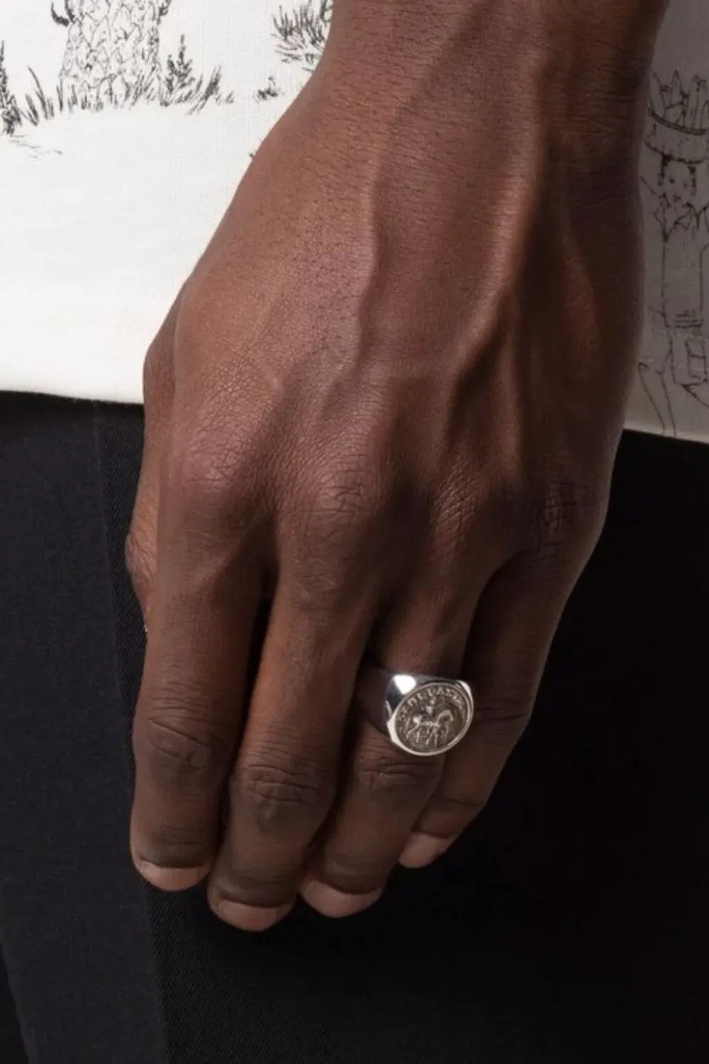 Close-up image of a man’s hand wearing the Tom Wood Alexander the Great coin signet ring, showcasing its embossed ancient coin motif set in polished sterling silver.