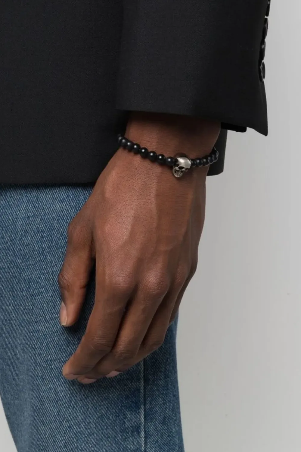Close-up of the Alexander McQueen Skull Beaded Bracelet, featuring matte black beads and a signature skull charm in polished metal.