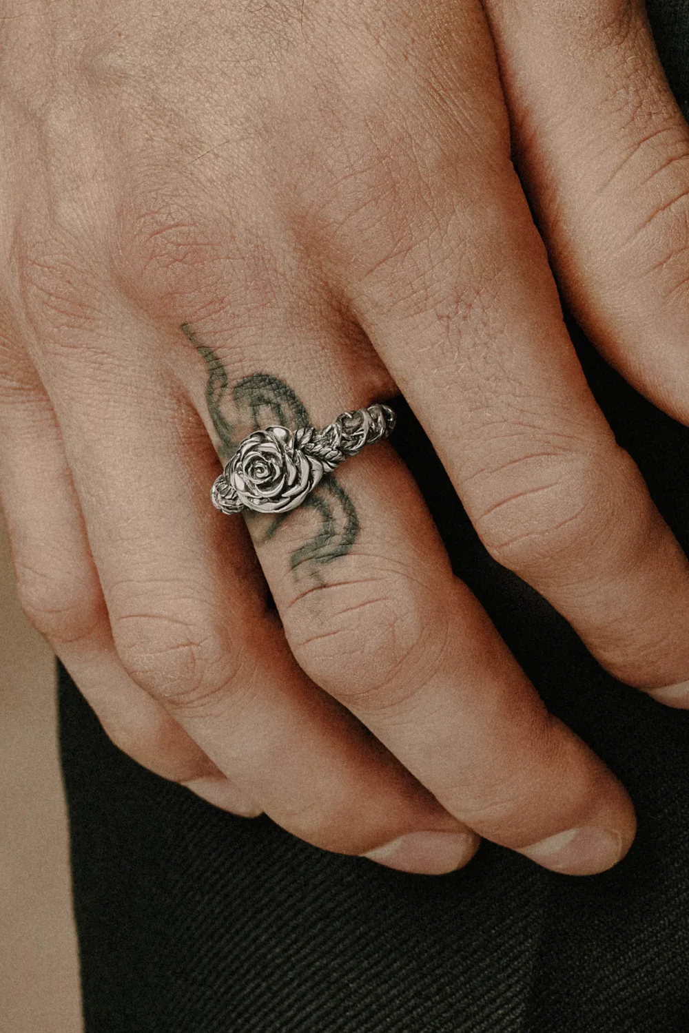 Close-up image of a man’s hand wearing the Clocks and Colours “All Apologies” sterling silver ring, highlighting its bold rose motif and oxidized detailing for a rugged finish.