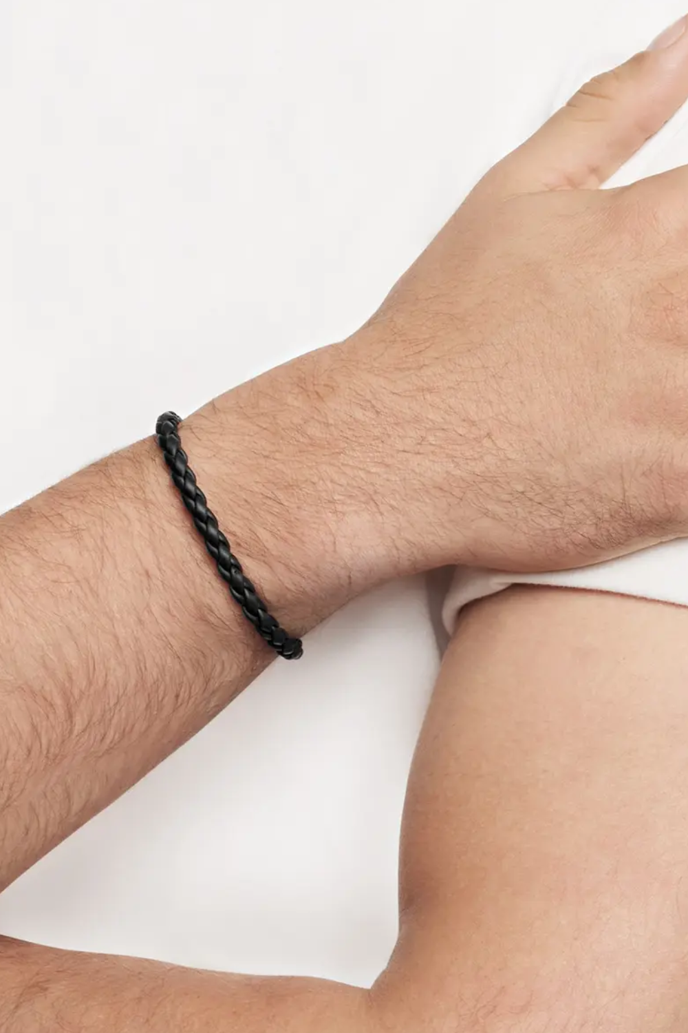 Close-up of a man’s arm wearing the David Yurman Chevron Braided Rubber Bracelet while resting his hand across the opposite arm, showing its bold, modern texture.