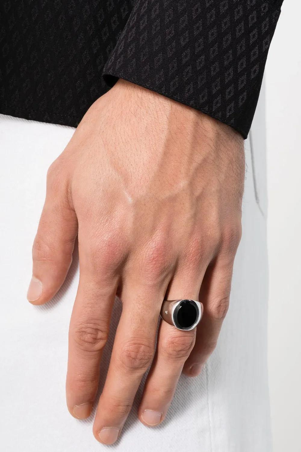 Close-up shot of a man’s hand wearing the Tom Wood oval polished onyx ring, featuring a sleek black onyx stone set in a smooth sterling silver frame with a mirror-like finish.