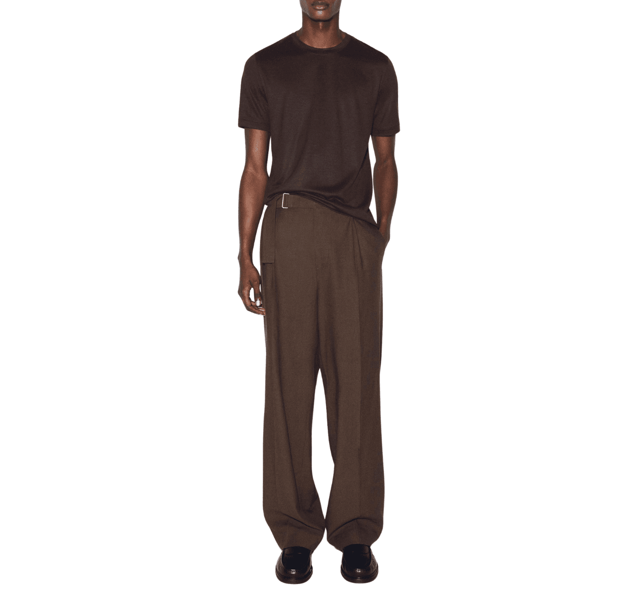 Man wearing a dark brown T-shirt with chocolate brown pants and black leather loafers, standing with one hand in his pants pocket.