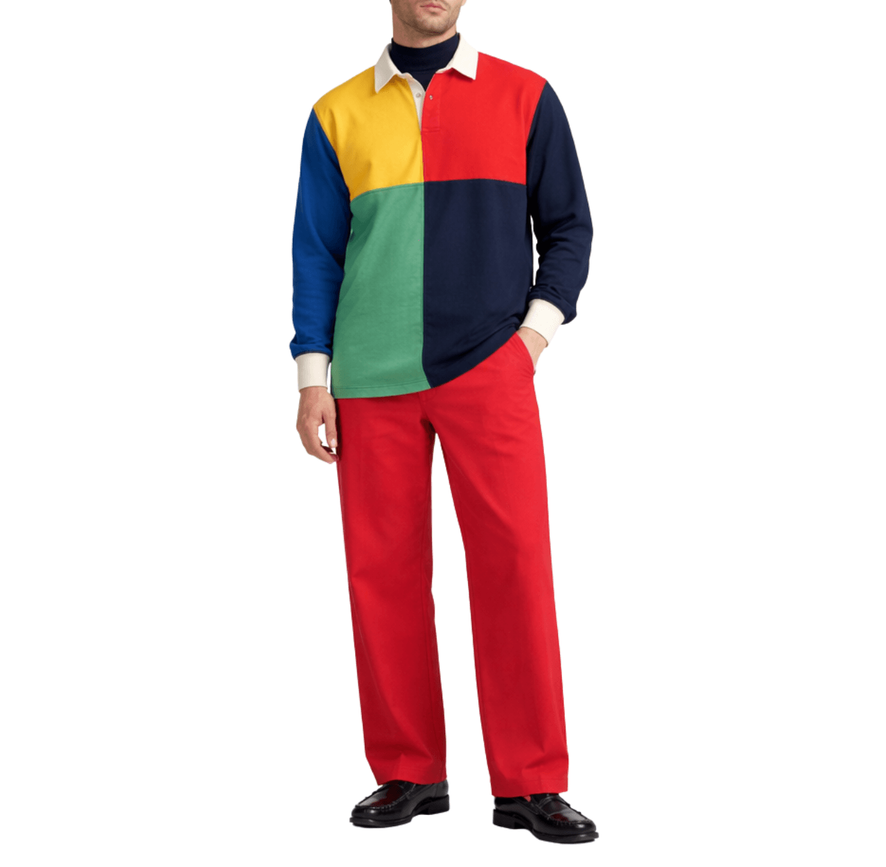 Man wearing a multi-paneled rugby shirt with red pants and black leather loafers, standing with one hand in his pants pocket.