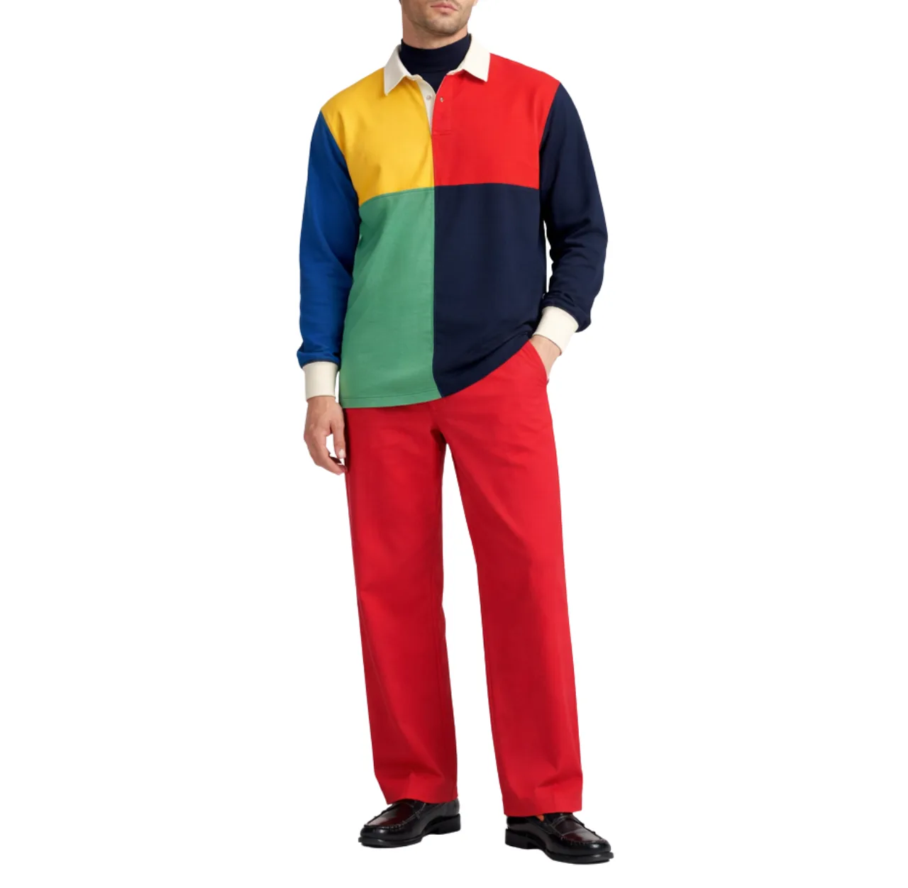 Man wearing a multi-paneled rugby shirt with red pants and black leather loafers, standing with one hand in his pants pocket.