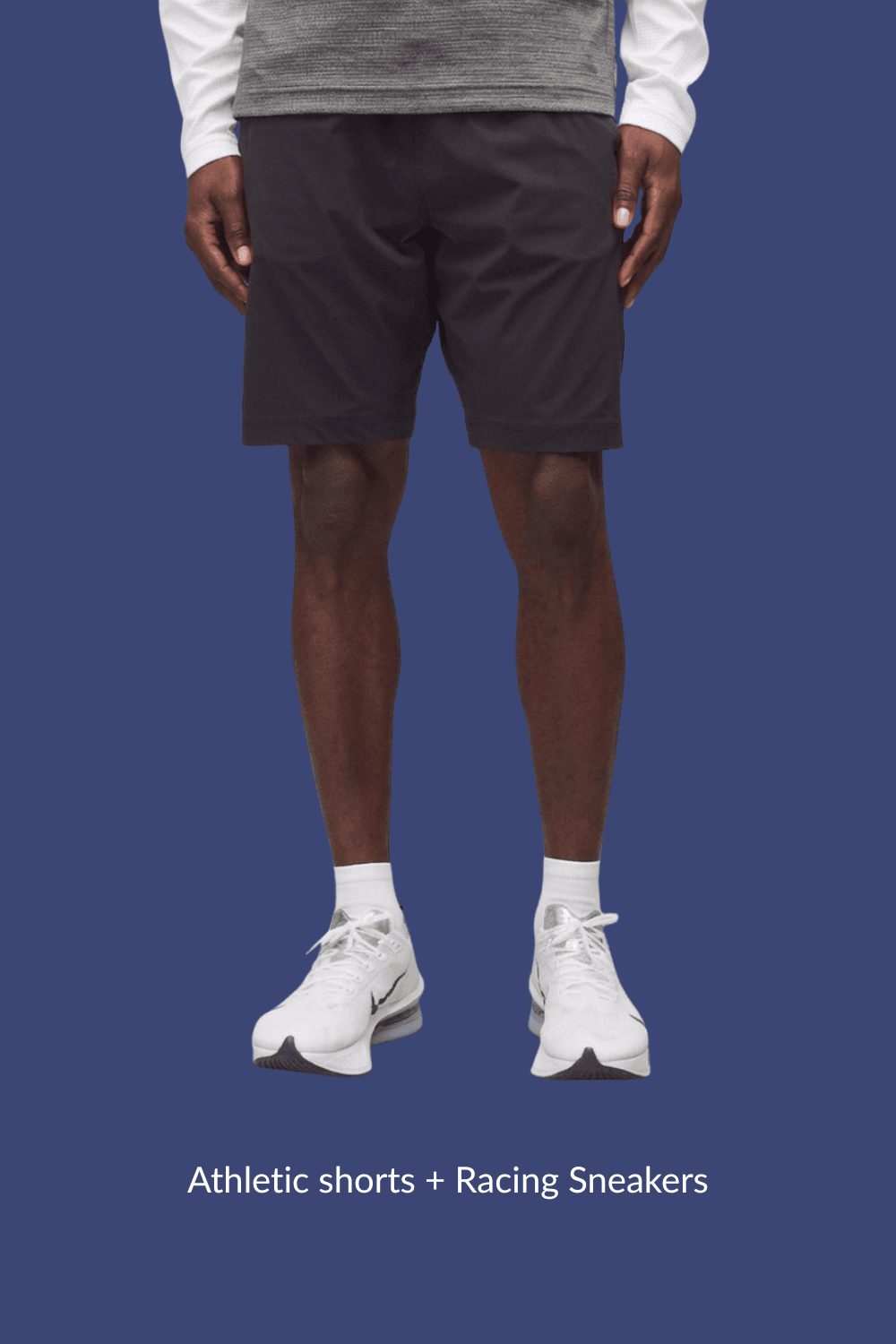 Man wearing black athletic shorts and white Nike racing shoes, standing casually with arms relaxed at sides.