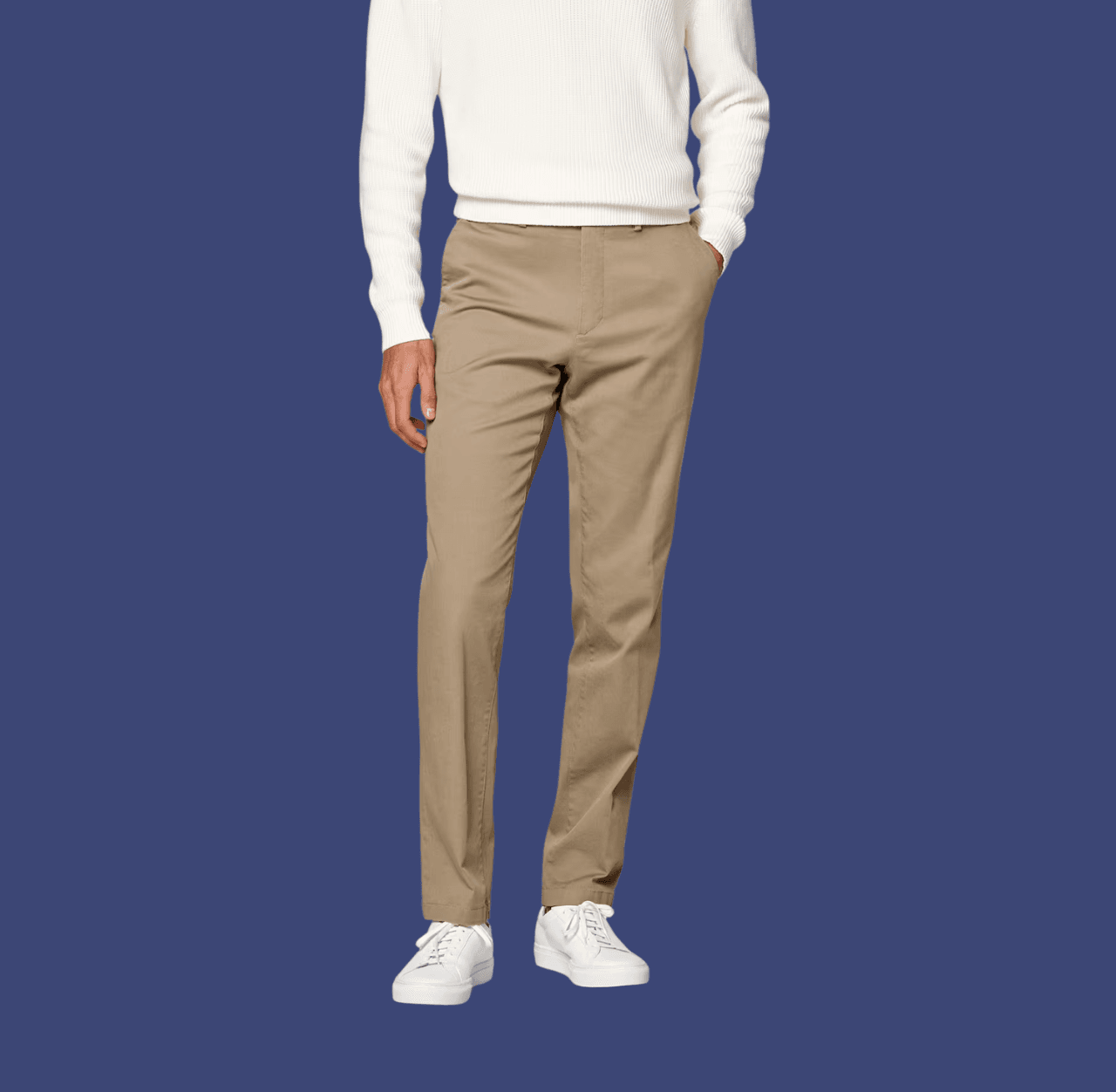 Man wearing khaki chino pants and white leather sneakers, standing casually with one hand in his pocket.