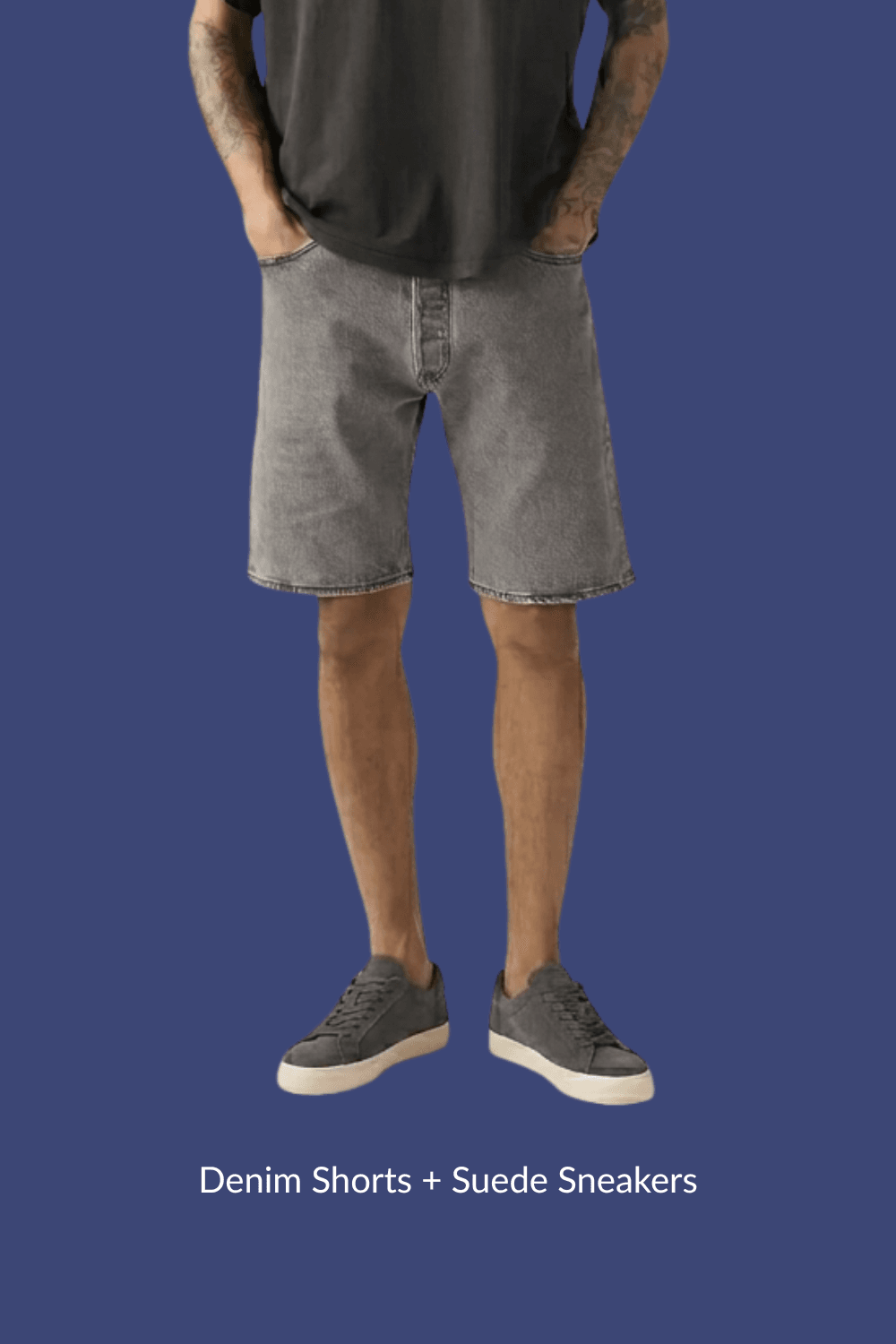 Man in gray denim shorts and gray suede sneakers with hands in pockets, standing casually.