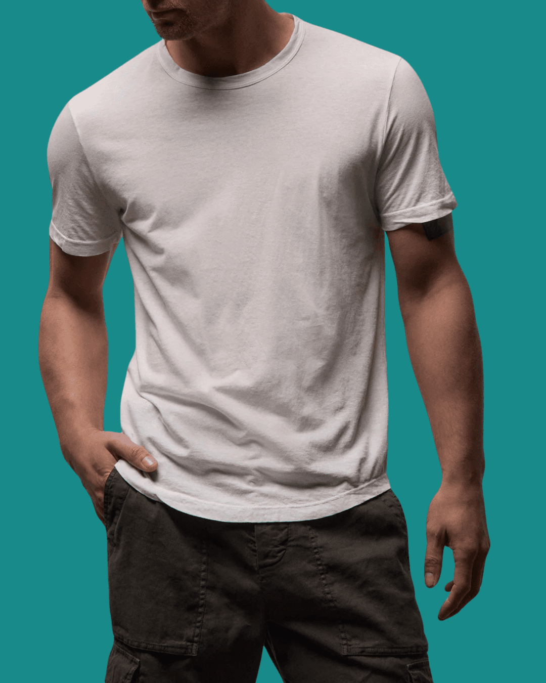 Man in James Perse Clear Jersey Crew Neck White Tee with a hand in pockets, standing casually.