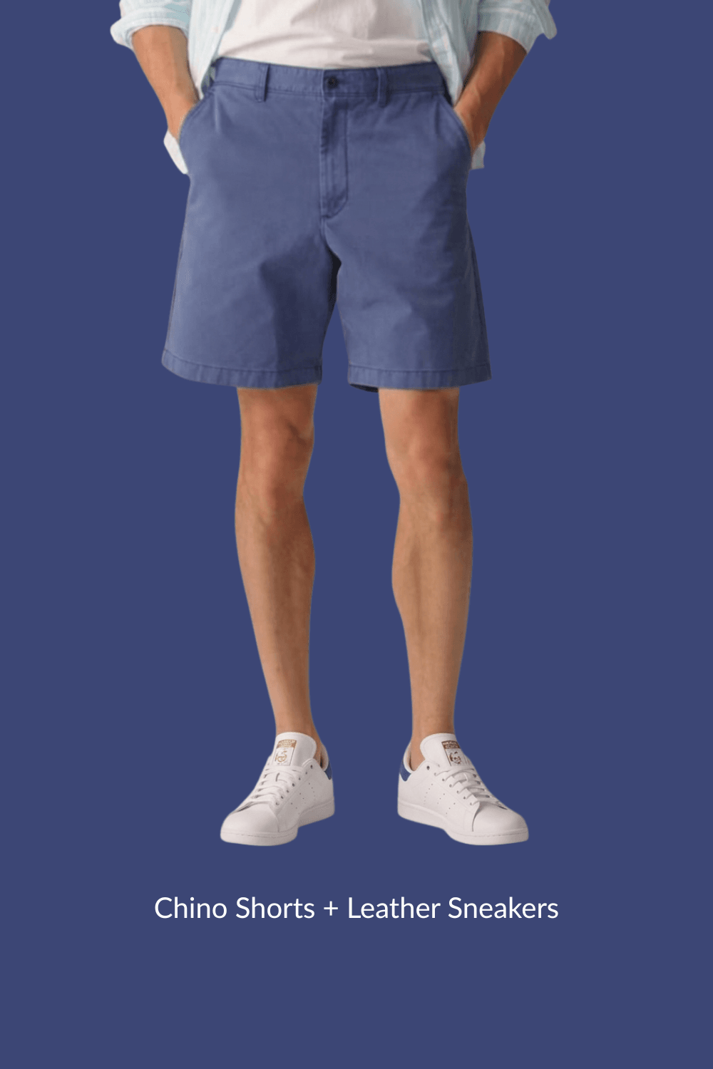 Man in blue chino shorts and white leather sneakers with hands in pockets, standing casually.