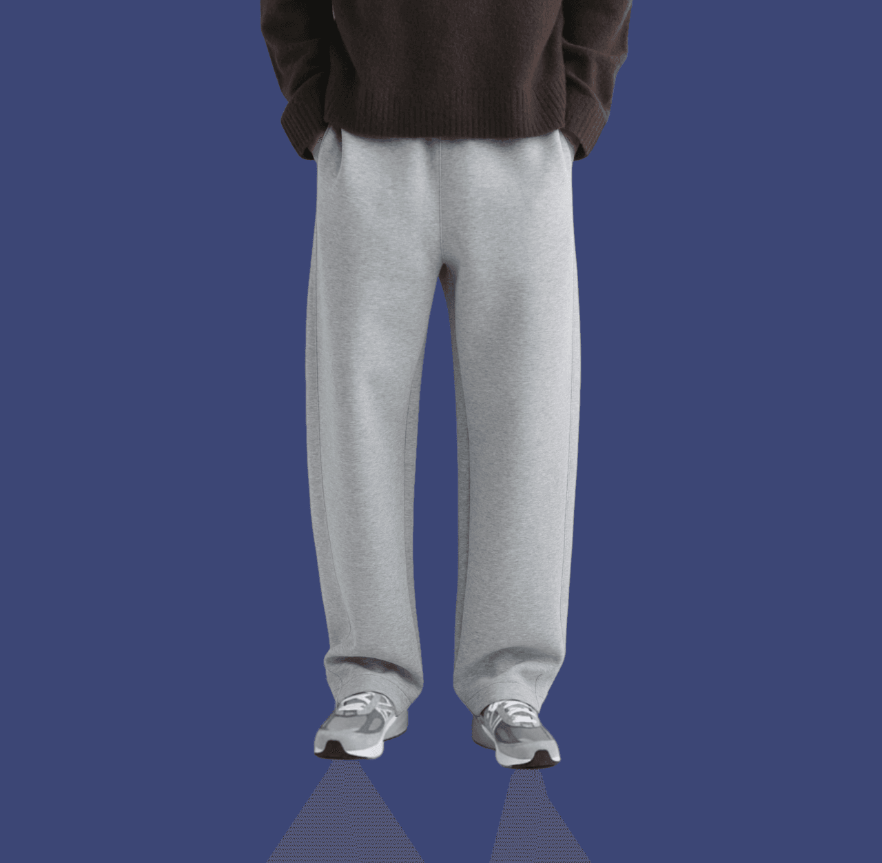 Man in gray wide joggers and gray New Balance sneakers with hands in pockets, standing casually.