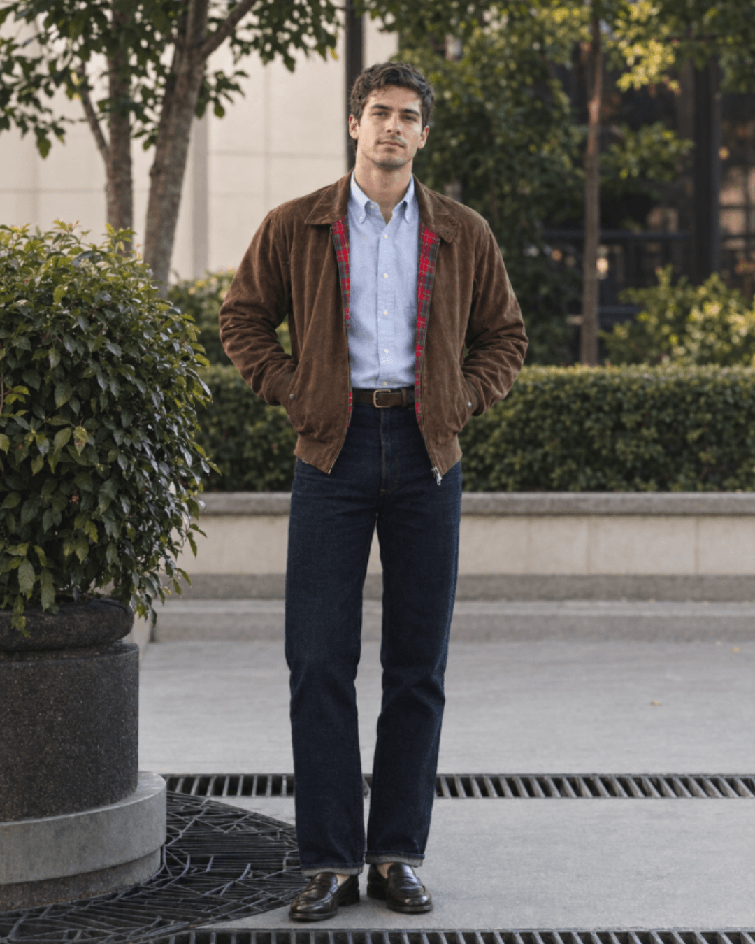 Man wearing a suede Harrington jacket, an Oxford shirt, dark jeans, and leather loafer
