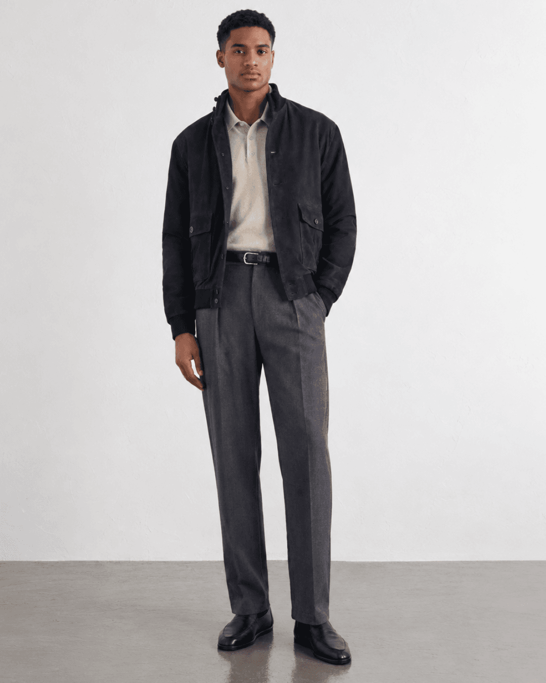 Man wearing a suede blouson, a fine-gauge knit polo and tailored trousers