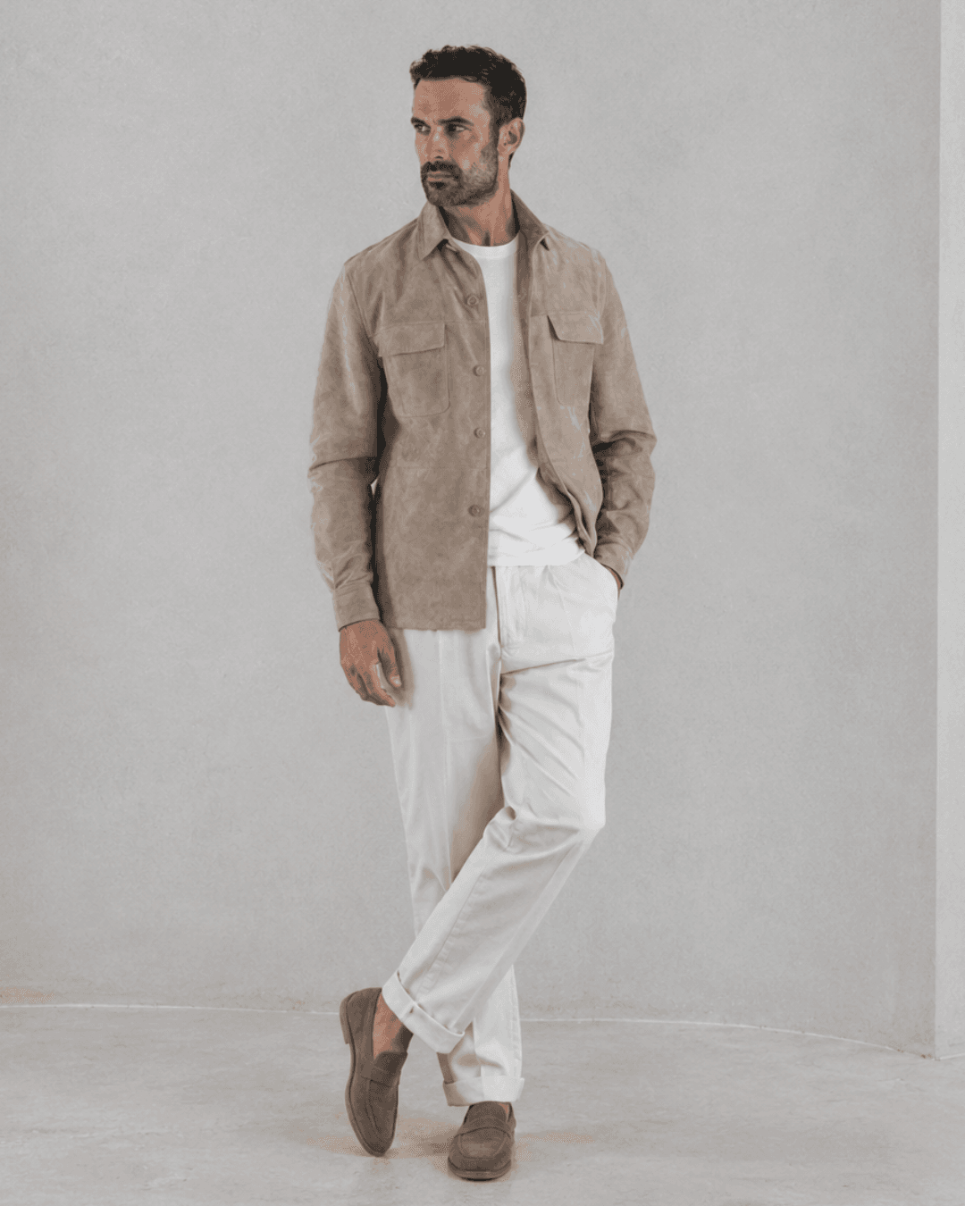 Man wearing a suede shirt jacket, a white tee, white chinos, and suede loafers