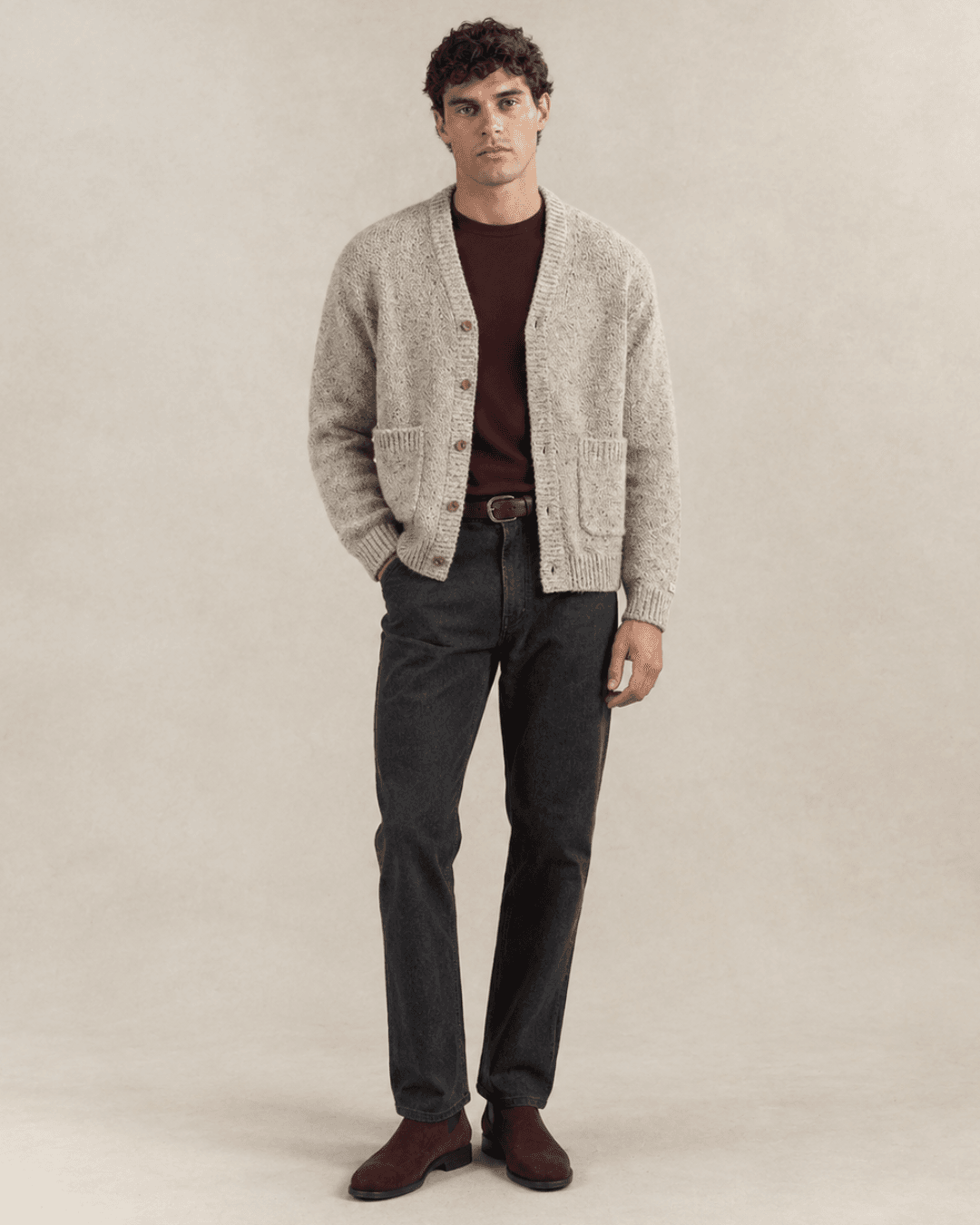 Man wearing an Oatmeal cardigan jacket, a Burgundy T-shirt, Charcoal jeans, and Brown suede Chelsea boots