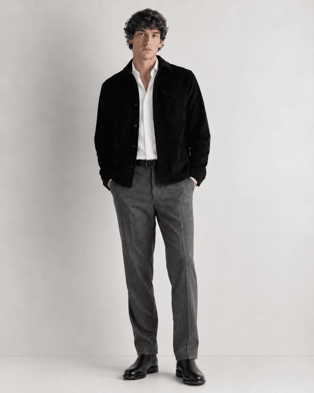 Man wearing a Black Overshirt, Gray Chalkstripe Trousers, a White Dress Shirt, Black Leather Chelsea Boots
