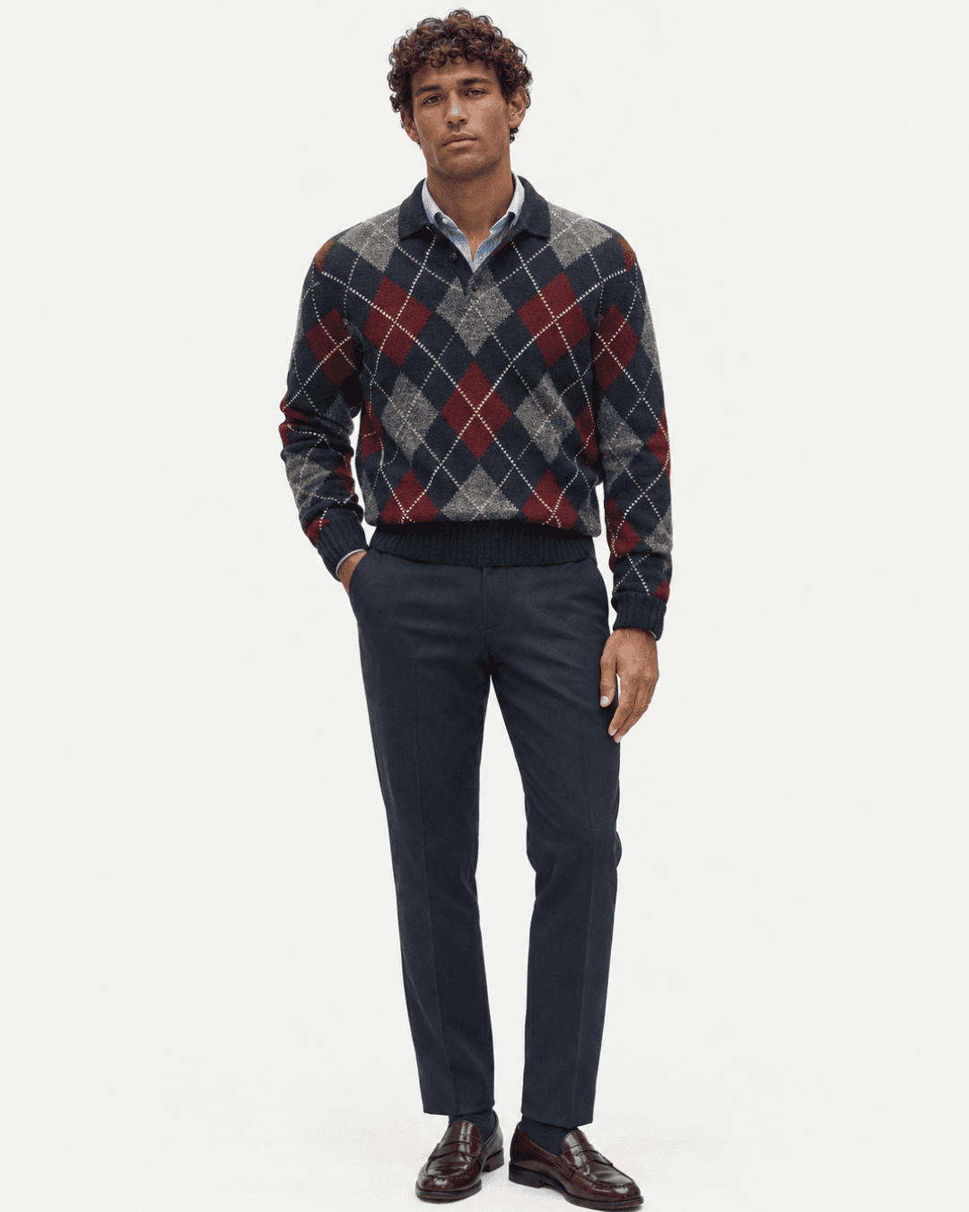 Man wearing an Argyle Sweater, a Blue Button Down, Navy Trousers , and Burgundy Leather Loafers